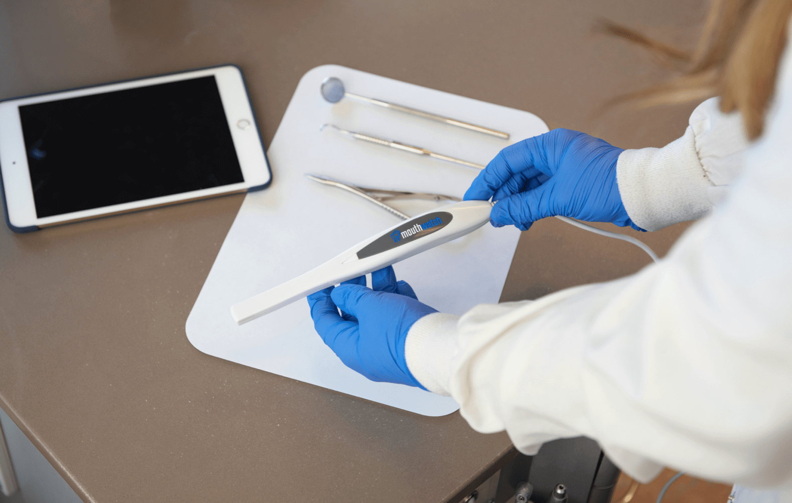 Image of technician looks at Intraoral Camera with other dental tools