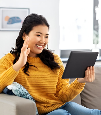 a woman in a yellow sweater on a couch using TeleDent teledentistry software on a tablet