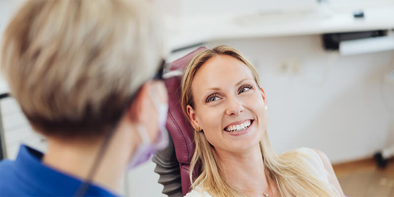 a blonde woman smiling while visiting the dentist