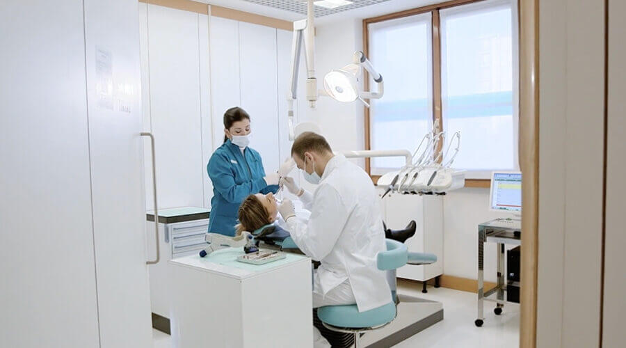 A dentist performs an oral examination of a patient 